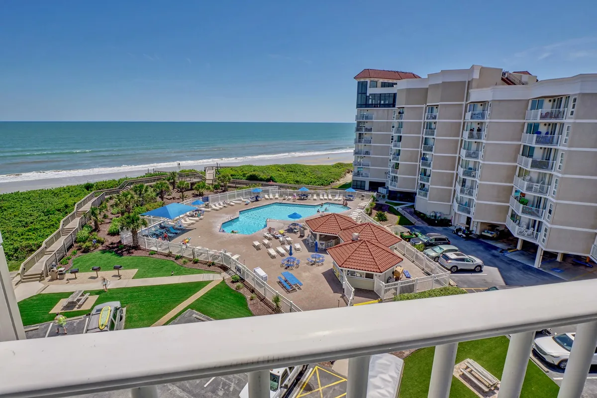 The image showcases a sparkling, brand new saltwater pool surrounded by lush landscaped gardens, with a sweeping balcony view overlooking the Atlantic Ocean. Sunlight dances on the water, inviting guests to relax poolside, take a refreshing swim, or gaze out at the sunrise beyond the beach below.