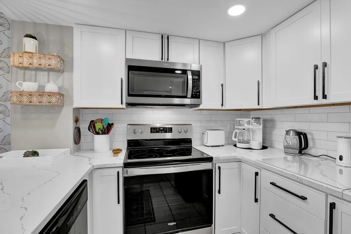 A modern kitchen space anchored by gleaming stainless steel appliances, marble countertops, and open shelving adorned with decorative items. The layout encourages cooking and entertaining, and the inviting mood reflects family-friendly functionality.