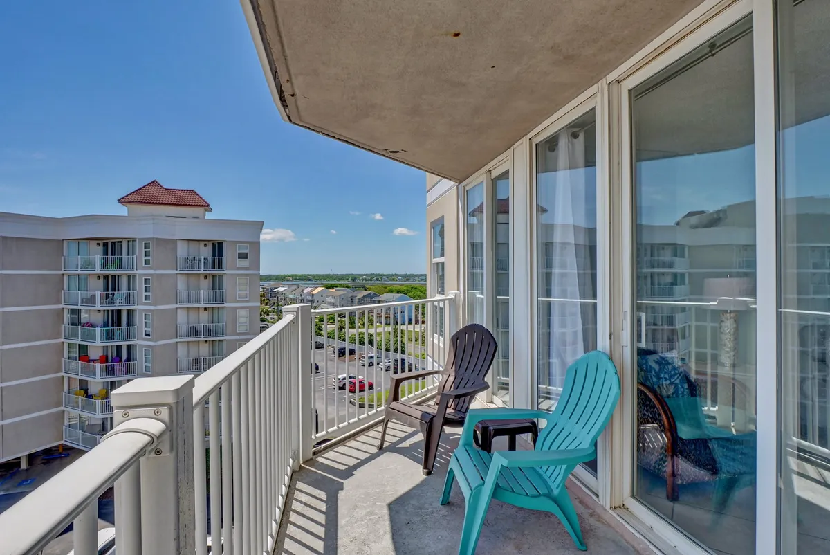 A serene exterior balcony setup with comfortable seating, overlooking the surrounding landscape and clear sky. The inviting space is perfect for relaxing, enjoying a morning coffee, or unwinding with a drink while taking in unobstructed views.